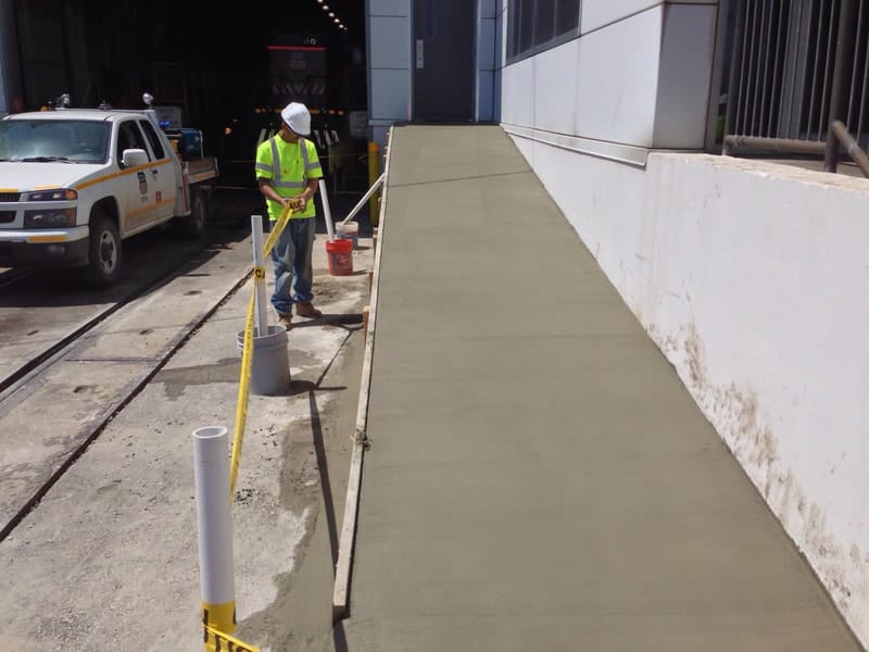 Concrete crew finishing a commercial sidewalk and ramp
