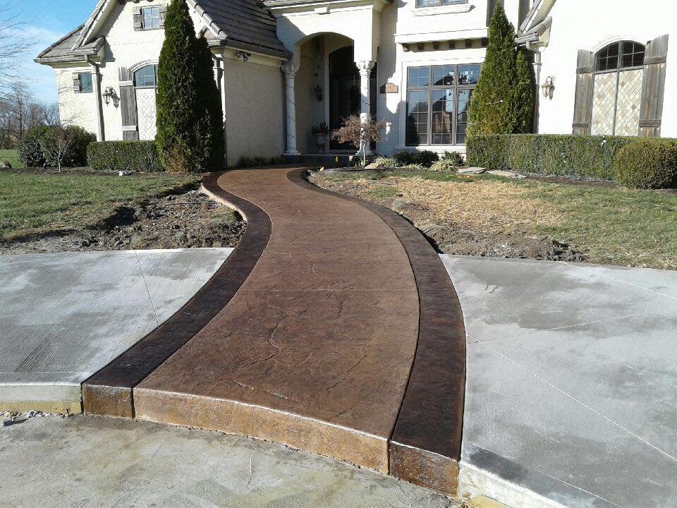 Long stamped concrete walkway leading to a large home